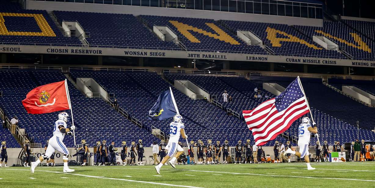 BYU's Tristen Hoge, Isaiah Kaufusi and Khyiris Tonga carry flags onto the field in Annapolis, Maryland before the start of the game against Navy, Monday, Sept. 7, 2020.