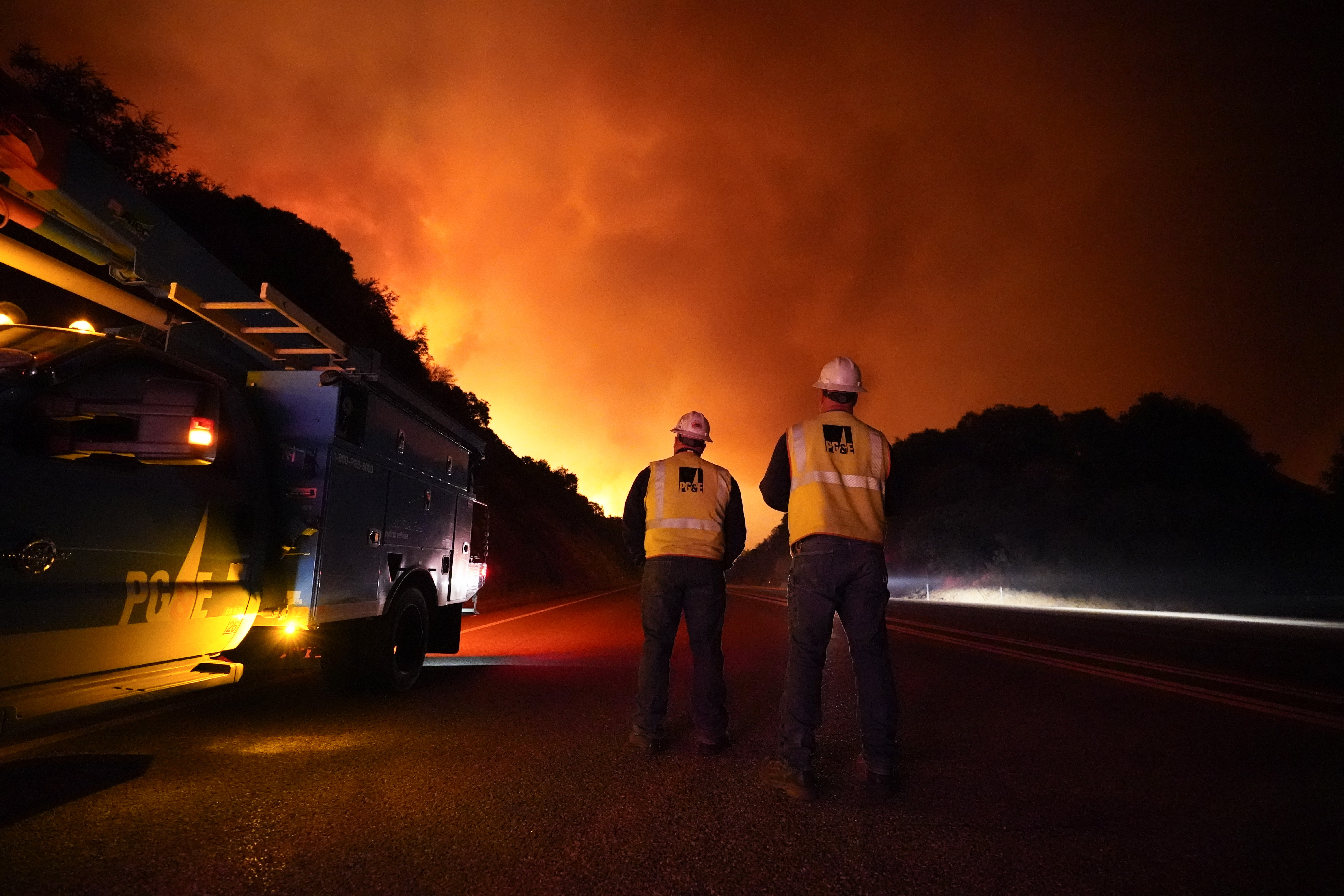 Pacific Gas and Electric workers stand along Highway 168 as the Creek Fire advances Tuesday, Sept. 8, 2020, near Alder Springs, Calif.