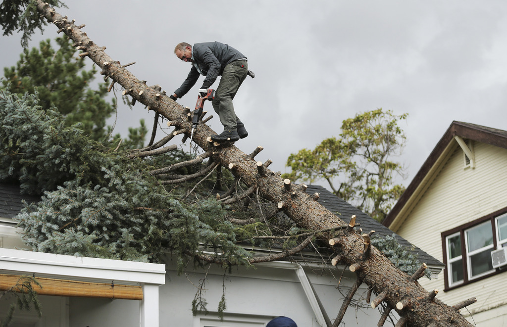 Joe Booth cuts the limbs off of a tree that fell on his house after high winds in the Avenues in Salt Lake City on Tuesday, Sept. 8, 2020.