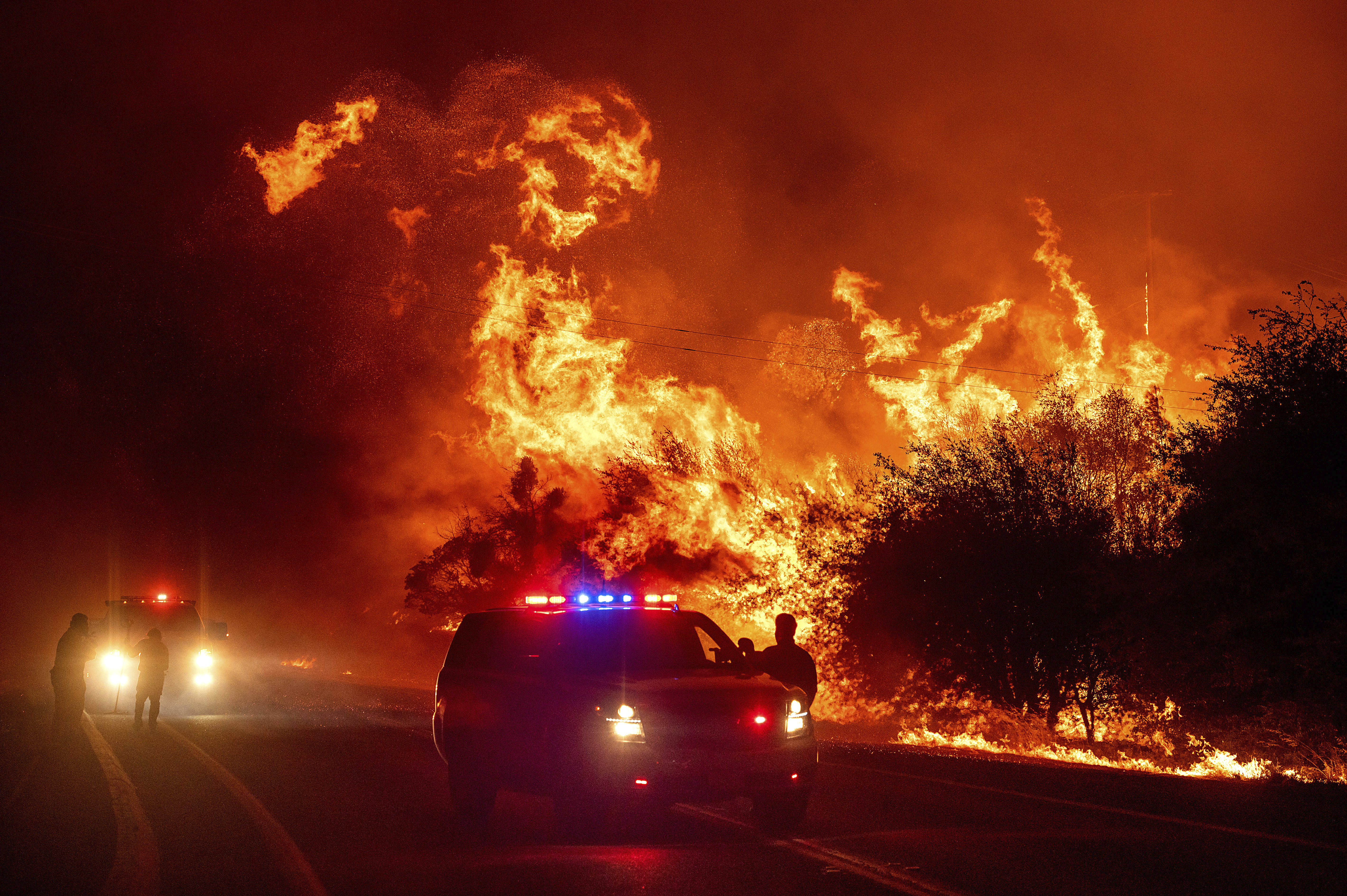 Flames lick above vehicles on Highway 162 as the Bear Fire burns in Oroville, Calif., on Wednesday, Sept. 9, 2020. The blaze, part of the lightning-sparked North Complex, expanded at a critical rate of spread as winds buffeted the region. (AP Photo/Noah Berger) [Sep-09-2020]