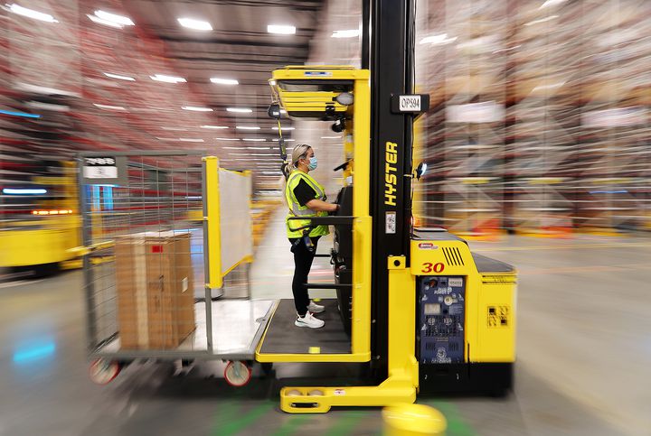 A worker operates a lift as it moves from aisle to aisle retreating products inside the newly opened Amazon fulfillment center in West Jordan on Monday, Sept. 14, 2020.