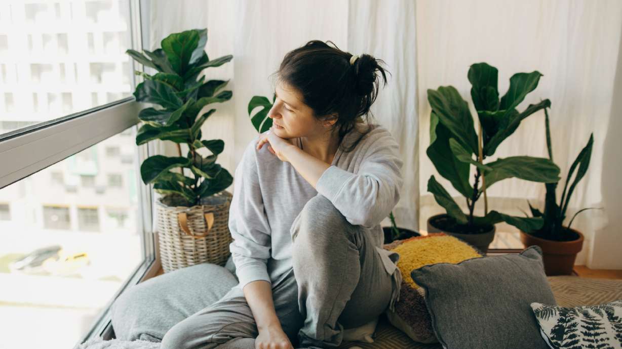 A young woman looks out a window. Students within the System of Higher Education are eligible for peer coaching through the Trula Foundation.