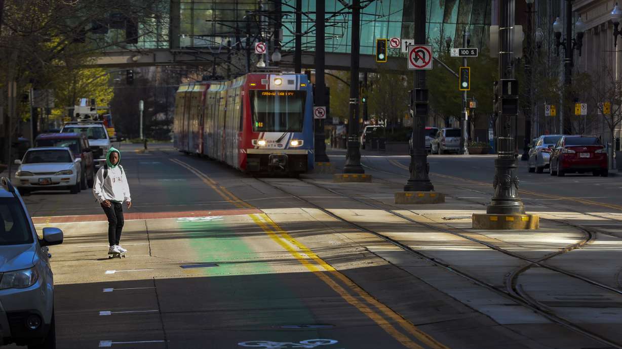 A skateboarder shares empty Main Street with a TRAX train during the morning commute in Salt Lake City on Monday, April 13, 2020. The normally bustling streets were empty due to the COVID-19 pandemic.