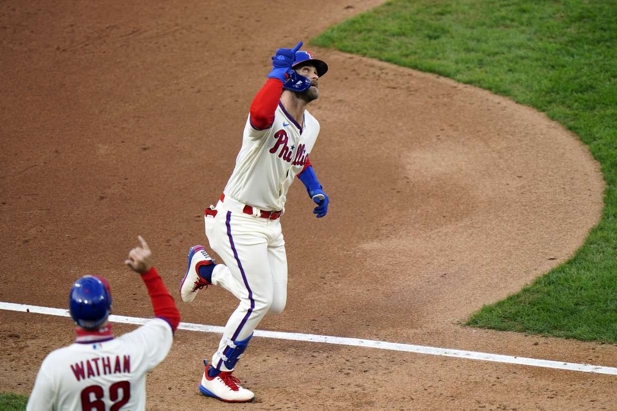 Philadelphia Phillies' Bryce Harper, right, reacts with third base coach Dusty Wathan after hitting a two-run home run off Toronto Blue Jays pitcher Robbie Ray during the fifth inning of the first baseball game in a doubleheader, Friday, Sept. 18, 2020, in Philadelphia.