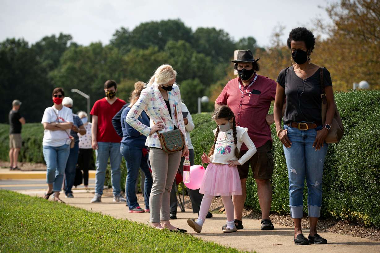 Laleh Daftarian, 6, plays with a balloon as she waits with her parents, Steven and Nataliia, in a socially distant line at an early voting site at the Fairfax County Government Center in Fairfax, Virginia, U.S., September 18, 2020.