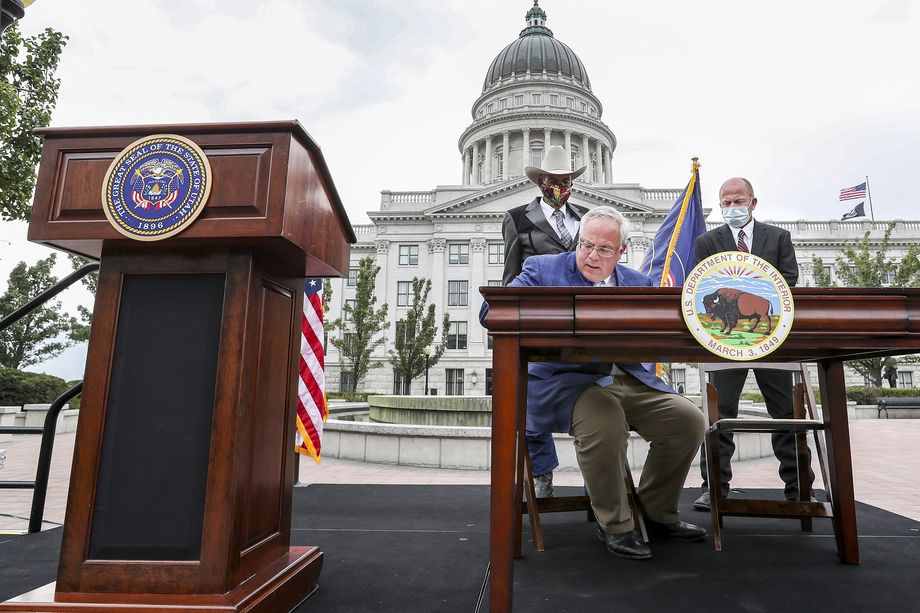 Interior Secretary David Bernhardt signs a document transferring ownership of two federal water projects to the state as Lee McElprang, chairman of the Emery County Conservancy District, back left, and Kirk Christensen, president of the Moon Lake Water Users Association’s board, back right, await their turn to sign the document during a ceremony outside of the Capitol in Salt Lake City on Friday, Sept. 18, 2020.