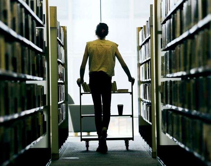 An employee at the Main Library in Salt Lake City pushes a cart between shelves of books on Monday, Sept. 21, 2020.