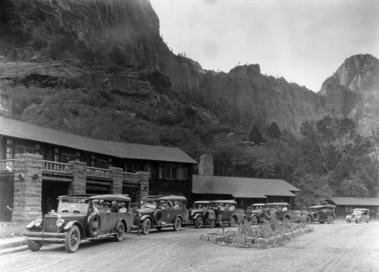 A photo of cars parked outside of the Zion Lodge at Zion National Park take in the 1920s. The Emerald Pools Trail was constructed not far from the lodge, on the other side of the Virgin River.