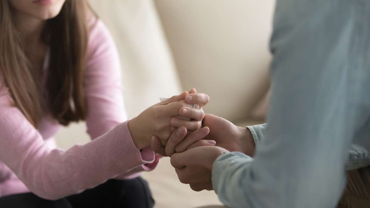 Close up view of upset couple, guy holding hands of crying woman, trying to comfort and console her, boyfriend apologizing offended lady, asking for forgiveness. Support, regret and compassion