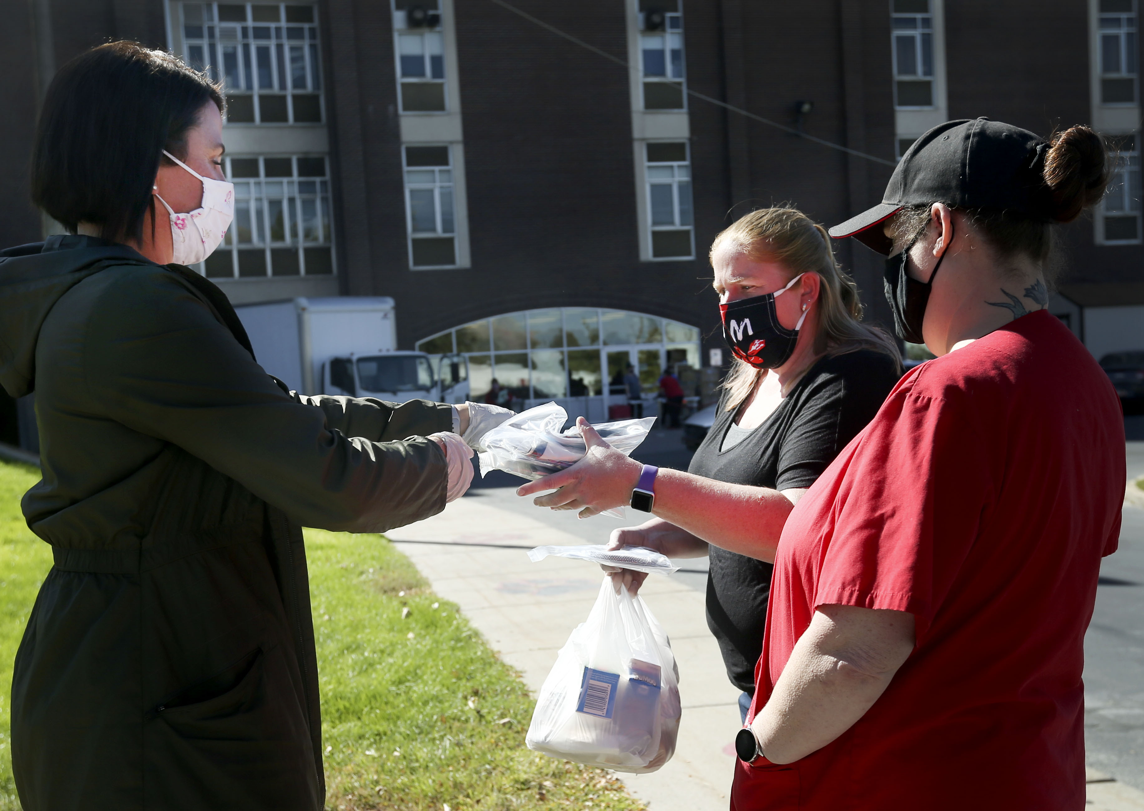Mary Catherine Perry, a parent of three Salt Lake City School District students, offers free masks to Linda Burrage and Janalee Gentry at a drive-thru meal pickup at Rose Park Elementary School in Salt Lake City on Wednesday, Sept. 30, 2020. Volunteers handed out 5,000 masks to help control the spread of COVID-19 and to support the safe and immediate return of students and teachers district classroom.
