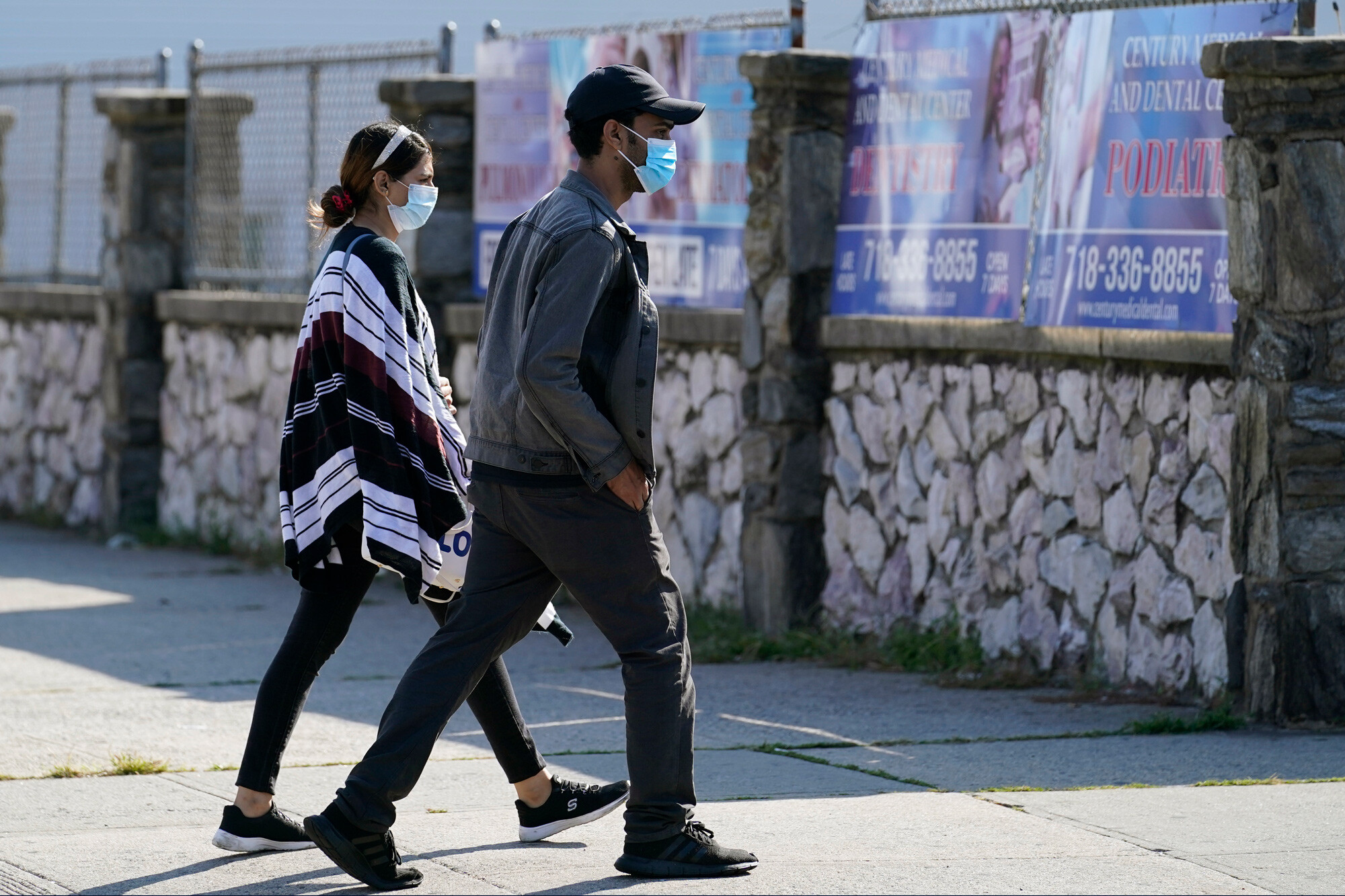 Two people wear protective face masks as they walk along a commercial street in the Gravesend section of the Brooklyn borough of New York on September 28, 2020.