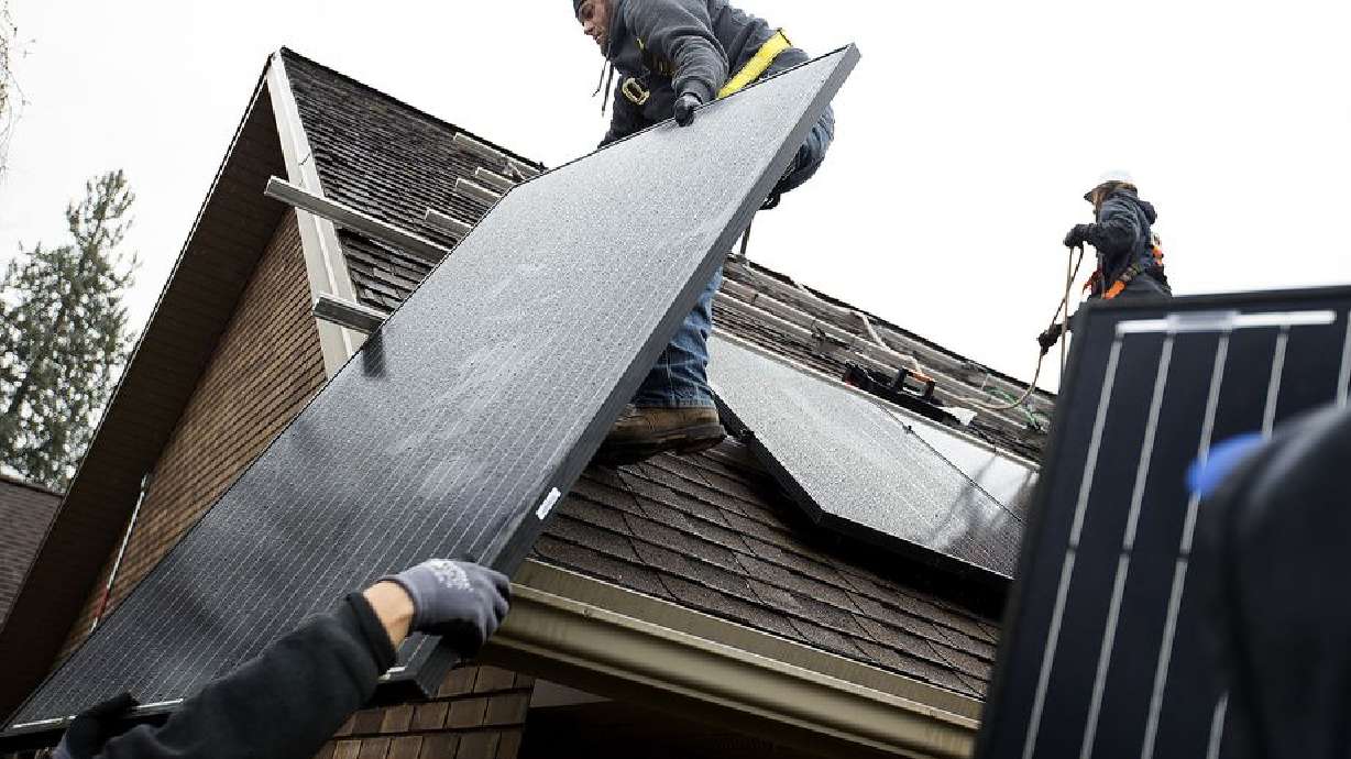 Justin Kourbelas and Tyler Eichmeier, of Go Solar Energy, install solar panels on a house in Holladay on Friday, April 6, 2018.