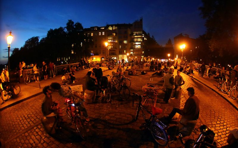 FILE PHOTO: People sit after sunset at the admiral bridge, a popular meeting point for tourists and residents, amid the coronavirus disease (COVID-19) outbreak, in Berlin, Germany, September 23, 2020. REUTERS/Hannibal Hanschke/File Photo