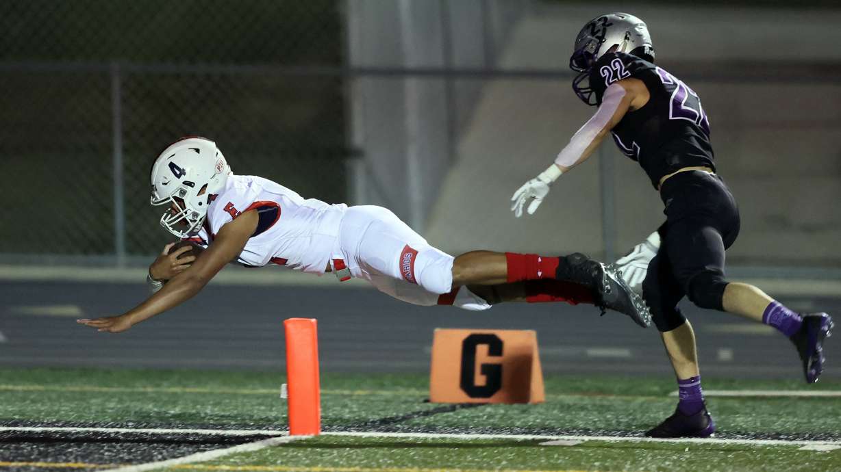 East's Siona Vailahi dives into the end zone for a score with Riverton's Colin Hauge chasing from behind as East and Riverton play football at Riverton on Friday, Oct. 9, 2020. East won 36-20.