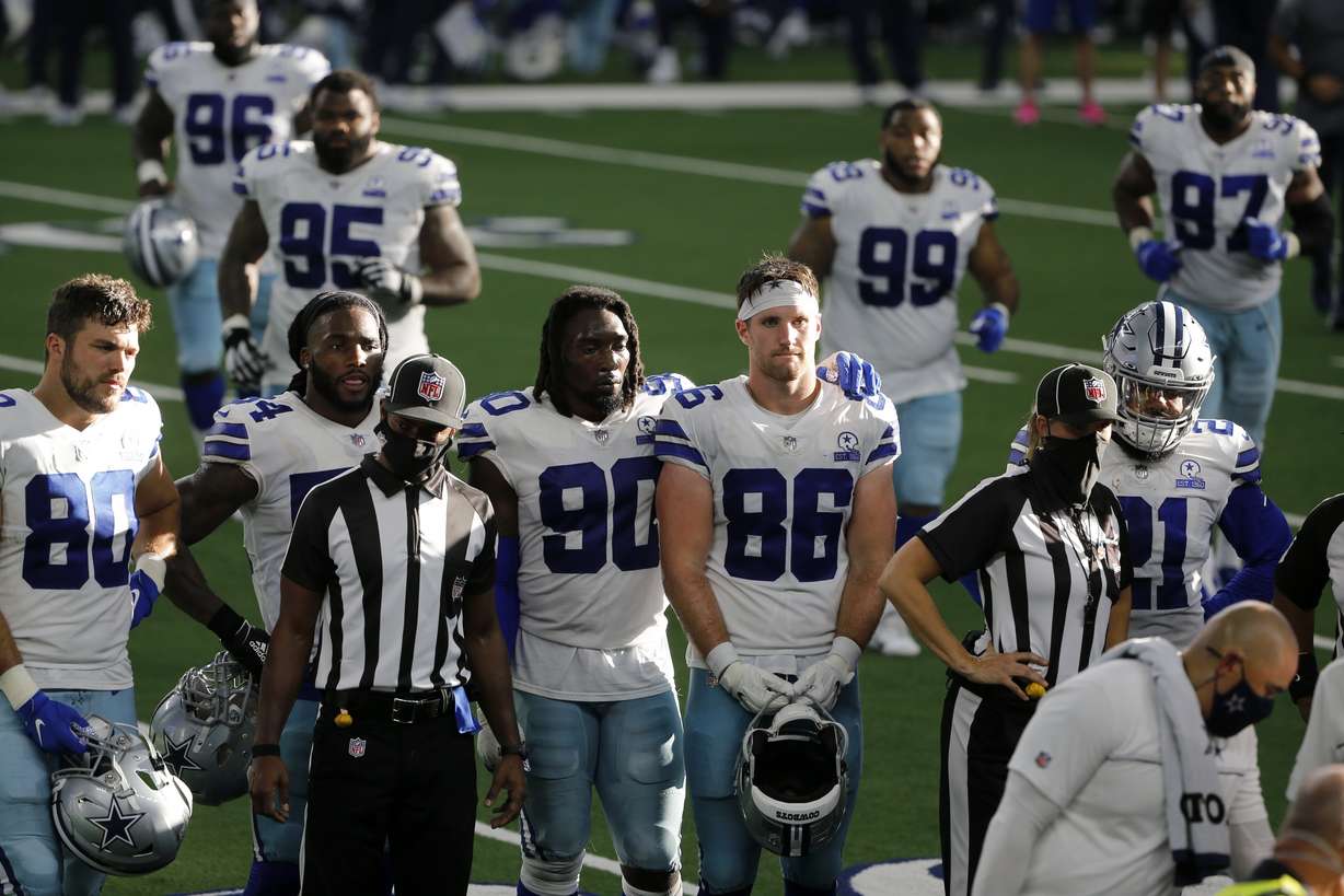Dallas Cowboys players, Blake Bell (80), DeMarcus Lawrence (90), Dalton Schultz (86), Ezekiel Elliott (21) and others look on as quarterback Dak Prescott, not shown, receives medical attention after suffering a lower right leg injury running the ball against the New York Giants in the second half of an NFL football game in Arlington, Texas, Sunday, Oct. 11, 2020.