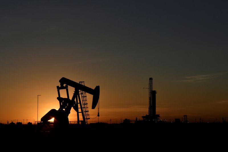 FILE PHOTO: A pump jack operates in front of a drilling rig at sunset in an oil field in Midland, Texas U.S. August 22, 2018. REUTERS/Nick Oxford