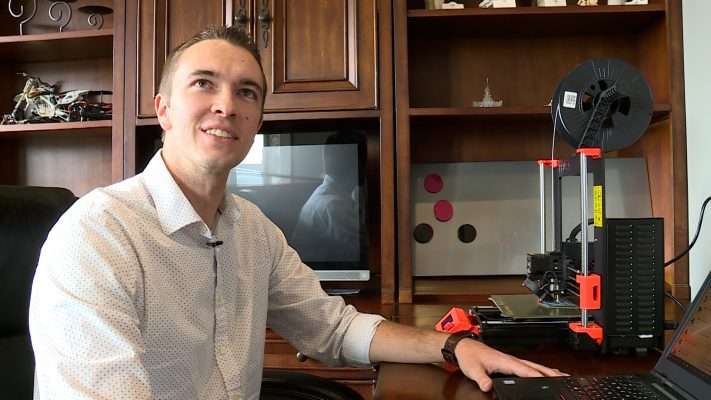 Bryan Stringham sits in front of his 3D printer.