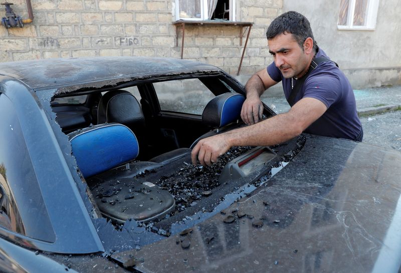 A man cleans his car from remains of glass which was broken during recent shelling during the military conflict over the breakaway region of Nagorno-Karabakh, in Stepanakert October 13, 2020. REUTERS/Stringer