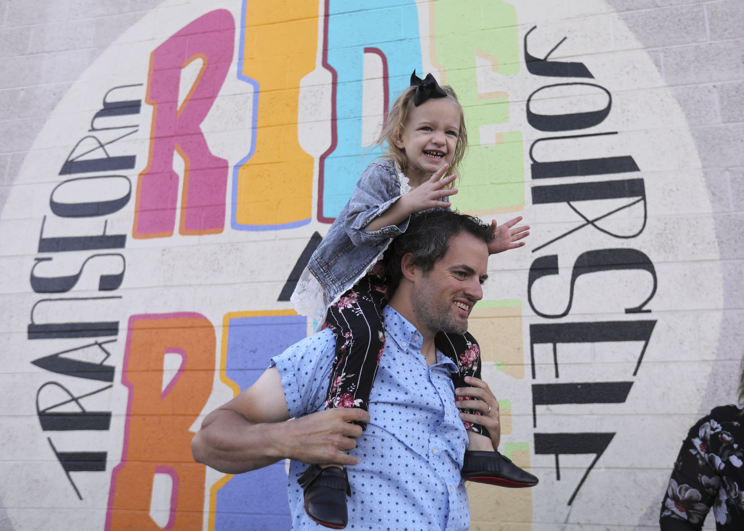 Mike West holds daughter Cozette West on his shoulders during a press conference about how biking has become their family's primary mode of transportation outside of the Bicycle Collective in Salt Lake City on Wednesday, Oct. 14, 2020. Data shows there has been an increase in walking and biking during the COVID-19 pandemic.