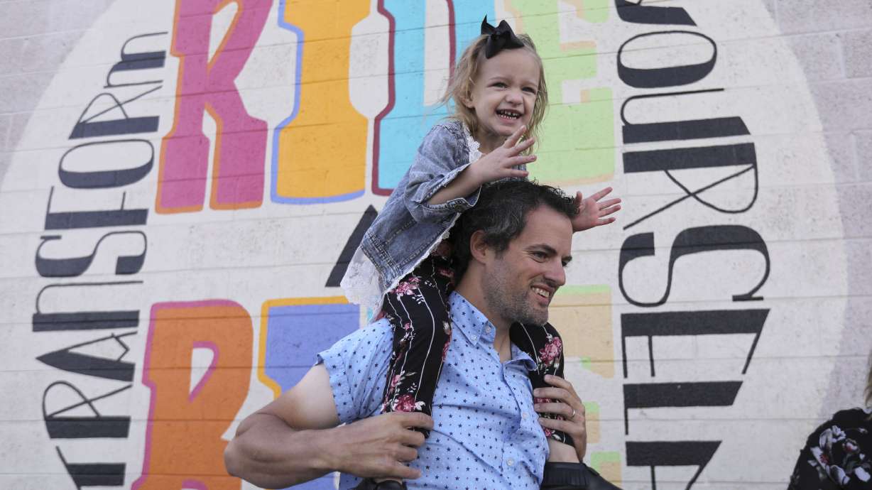 Mike West holds daughter Cozette West on his shoulders during a press conference about how biking has become their family's primary mode of transportation outside of the Bicycle Collective in Salt Lake City on Wednesday, Oct. 14, 2020. Data shows there has been an increase in walking and biking during the COVID-19 pandemic.
