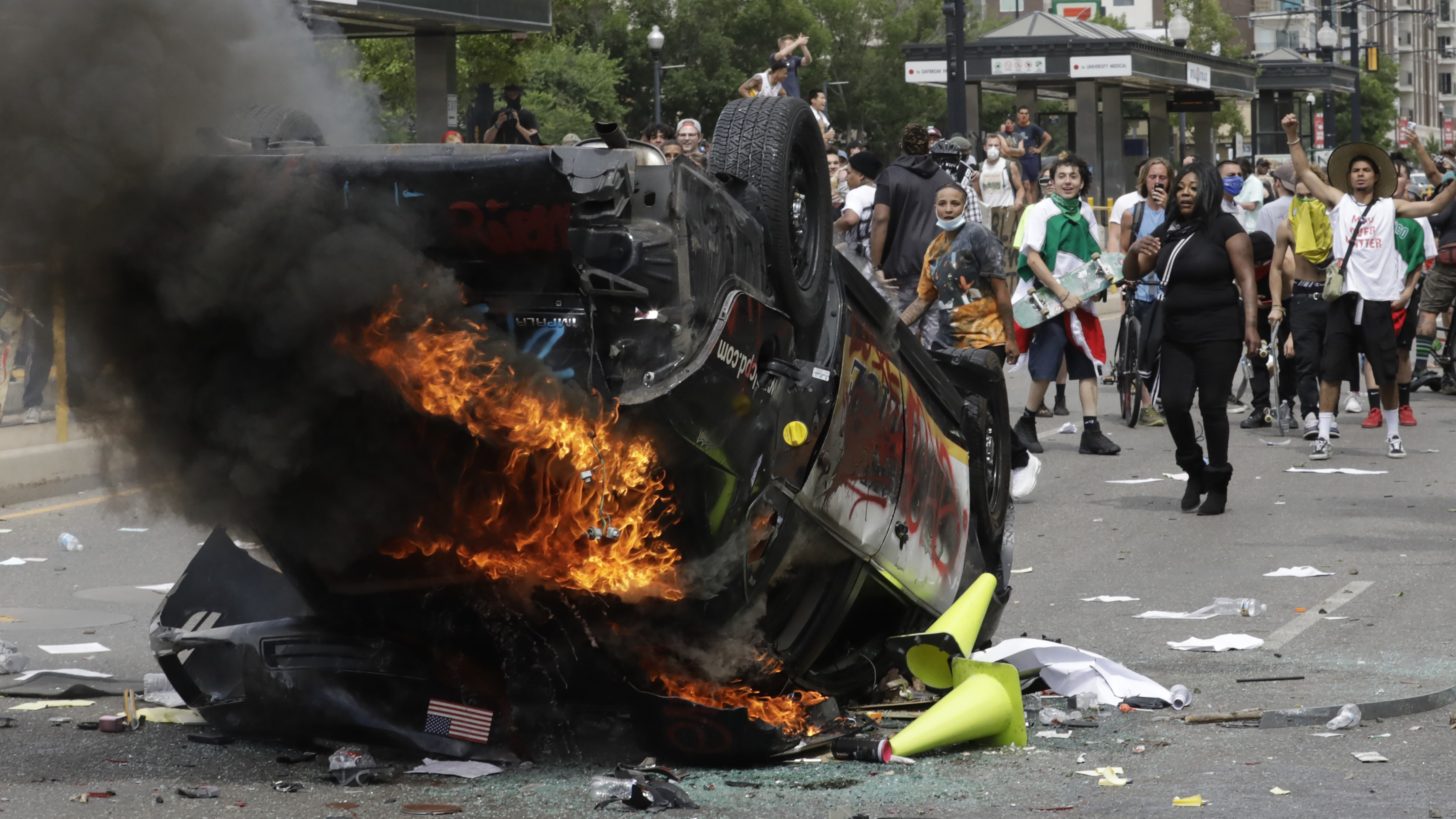 FILE - In this May 30, 2020, file photo, protesters demonstrate as a Salt Lake City police vehicle burns, in Salt Lake City. Investigators studied video footage to find Jackson Stuart Tamowski Patton, 26, who is accused of tossing a combustible substance into the patrol car, feeding the flames that destroyed it, prosecutors said in court documents. The Department of Justice is using aggressive tactics against those it has charged in the civil unrest over racism. (AP Photo/Rick Bowmer, File) [Oct-20-2020]