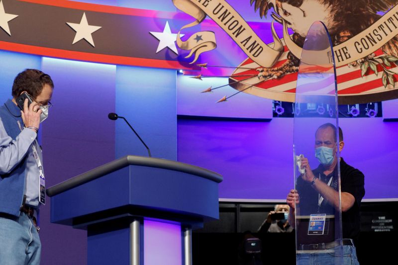 FILE PHOTO: A worker cleans the plexiglass shields onstage at the site of the second and final debate between 2020 U.S. presidential candidates President Donald Trump and Democratic nominee and former Vice President Joe Biden at the Curb Event Center that will host the October 22 debate at Belmont University in Nashville, Tennessee, U.S. Oct. 21, 2020. REUTERS/Jonathan Ernst/File Photo