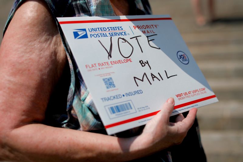 FILE PHOTO: A person holds a sign as U.S. Postal Service (USPS) workers rally on the steps of the James A. Farley Post Office in Manhattan calling for an end to mail delays, funding for the Postal Service and for the firing of U.S. Postmaster General Louis DeJoy in New York City, New York, U.S., August 25, 2020. REUTERS/Mike Segar/File Photo/File Photo/File Photo