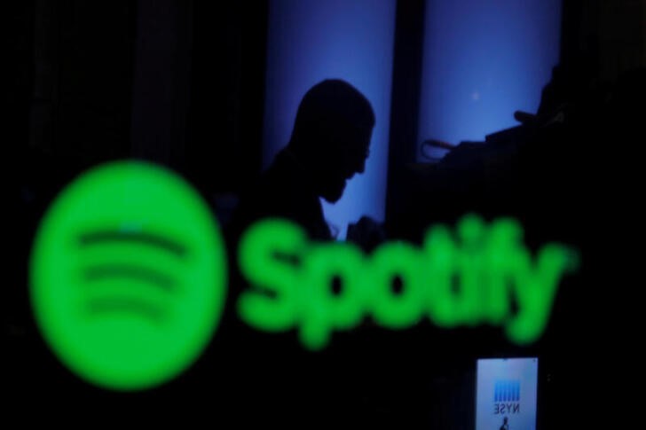 FILE PHOTO: A trader is reflected in a computer screen displaying the Spotify brand before the company begins selling as a direct listing on the floor of the New York Stock Exchange in New York, U.S., April 3, 2018.  REUTERS/Lucas Jackson/File Photo
