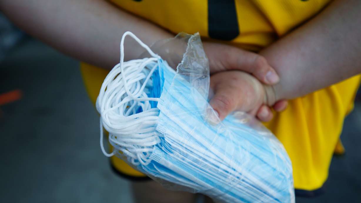 A Walmart employee holds a bag of face masks outside of the store in Orem on Monday, July 20, 2020, the first day the retail giant required all customers to wear a face masks to help slow the spread of COVID-19.