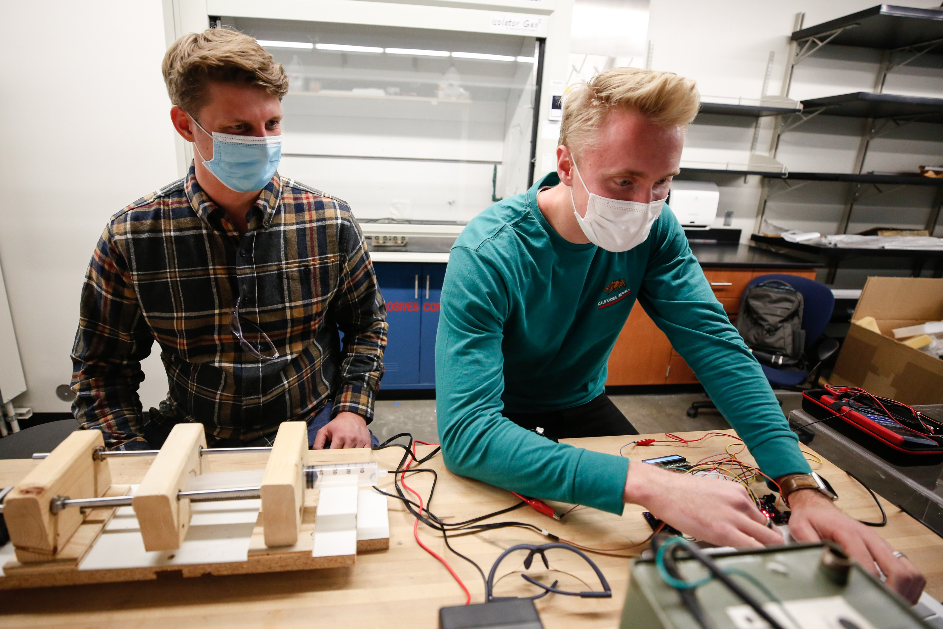 BYU mechanical engineering senior Denton Markwalter, left, works on a prototype of an electrical spinning machine with Spencer Curtis in the engineering resource lab at BYU in Provo on Monday, Oct. 26, 2020.Â The machine can be used to spin a nanofiber membrane that can be sandwiched between the cloth pieces of a homemade mask, increasing effectiveness while preserving breathability.