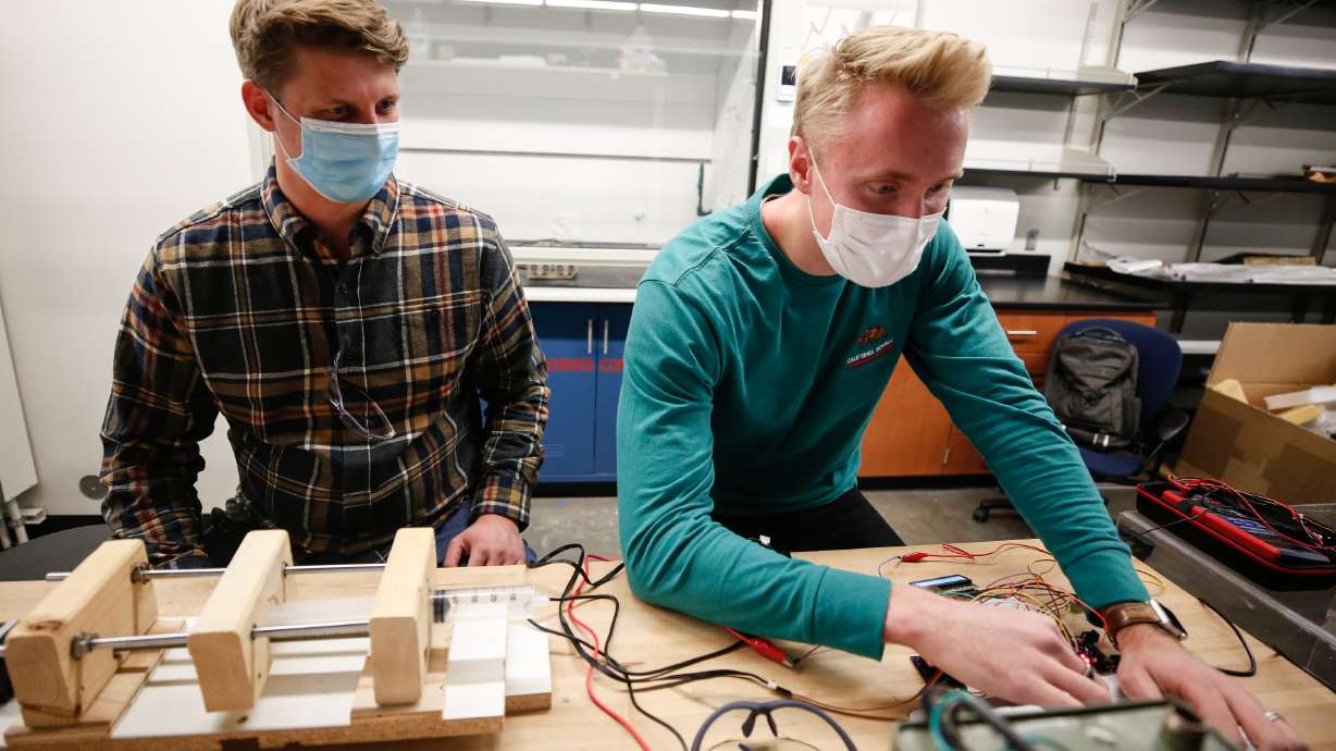 BYU mechanical engineering senior Denton Markwalter, left, works on a prototype of an electrical spinning machine with Spencer Curtis in the engineering resource lab at BYU in Provo on Monday, Oct. 26, 2020. The machine can be used to spin a nanofiber membrane that can be sandwiched between the cloth pieces of a homemade mask, increasing effectiveness while preserving breathability.