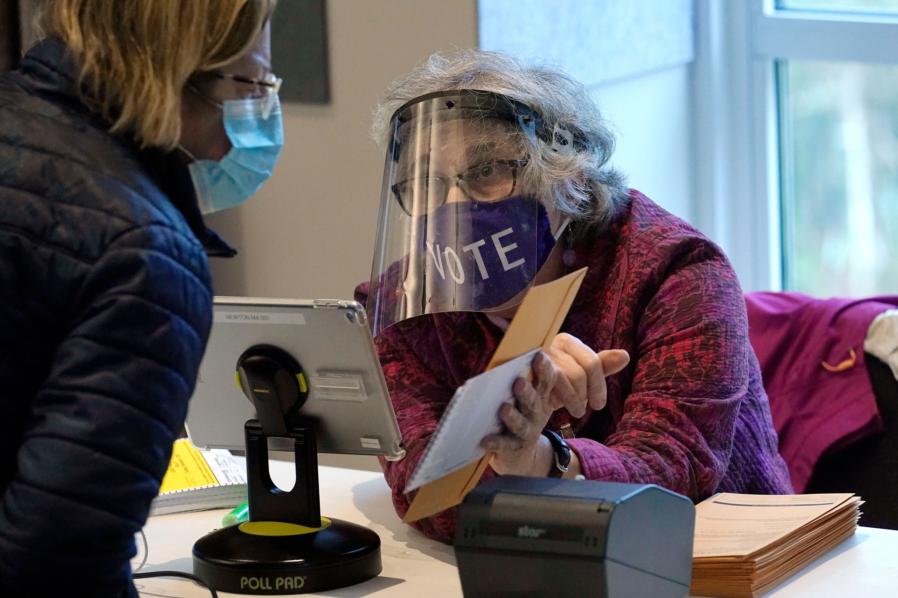 A well-protected poll worker in Newton, MA, cuts down on the risk of voting. Do your part by wearing a mask and social distancing.