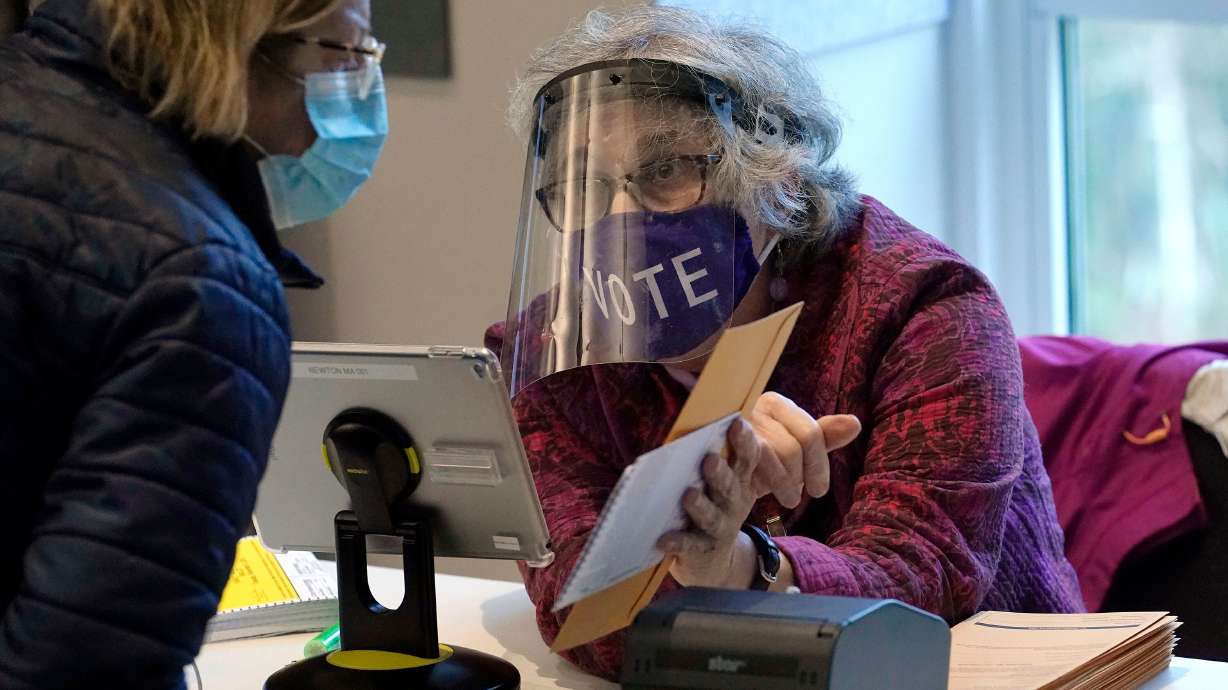 A well-protected poll worker in Newton, MA, cuts down on the risk of voting. Do your part by wearing a mask and social distancing.