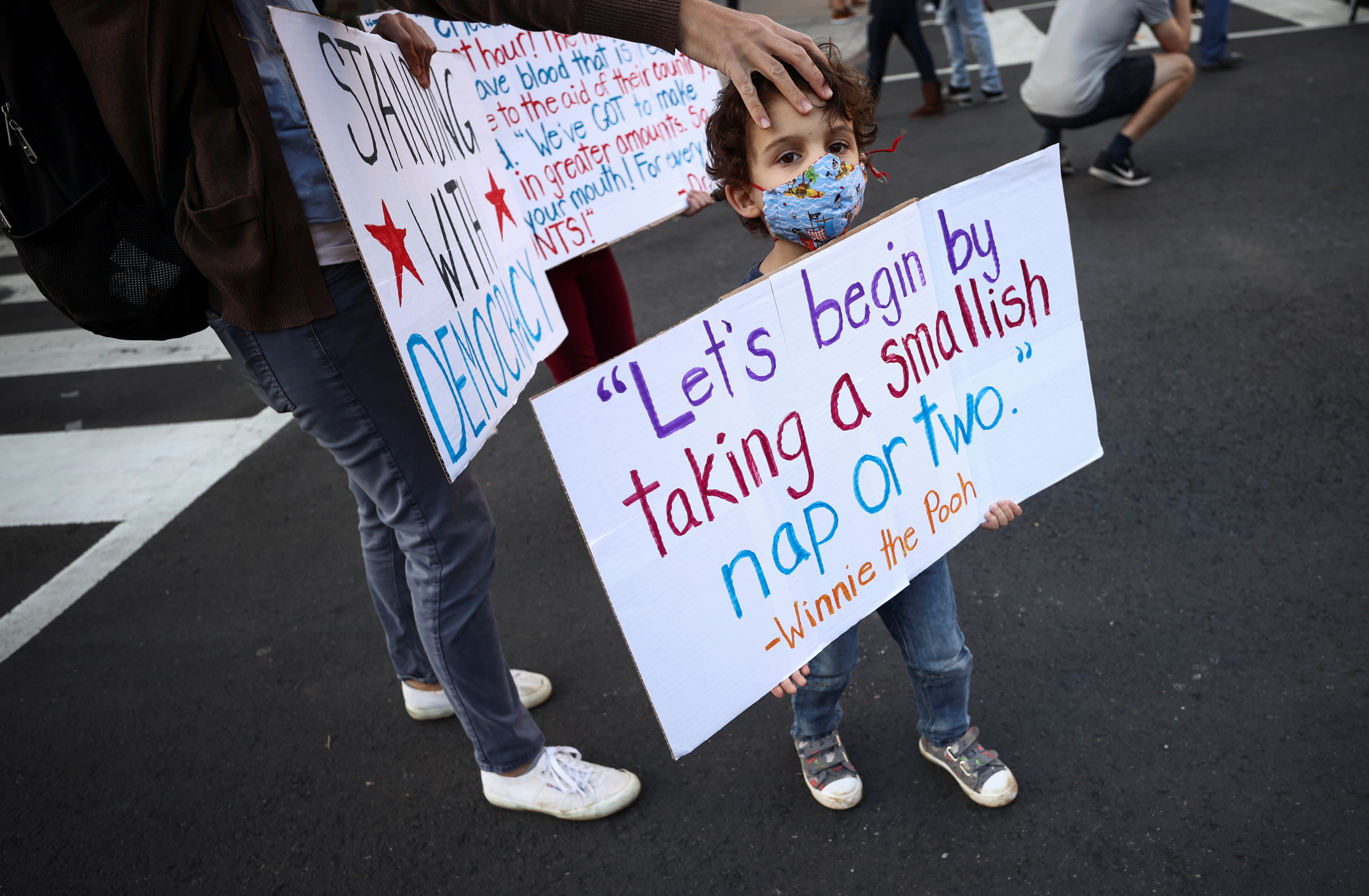 A kid wearing a face mask holds a sign at Black Lives Matter Plaza near the White House after Election Day in Washington, D.C., U.S., November 6, 2020.