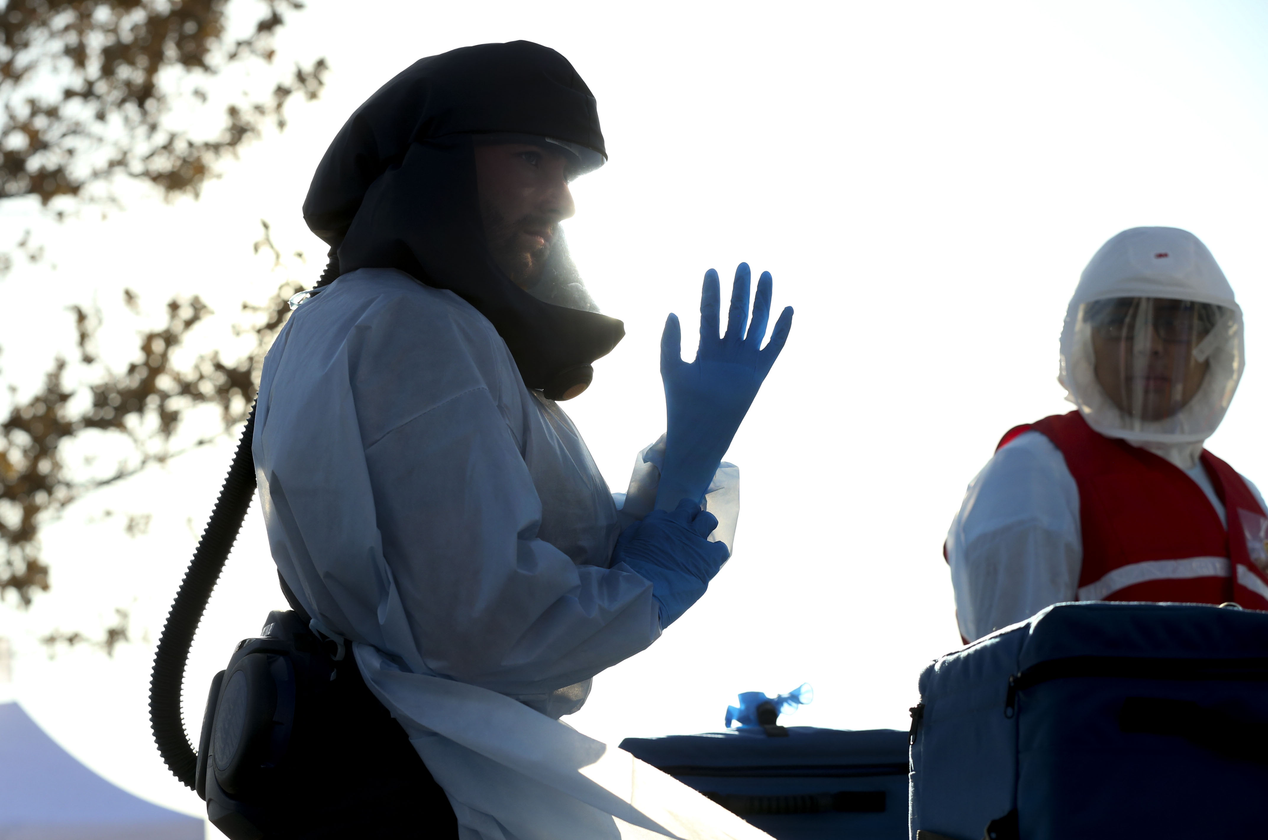 A worker puts on a pair of new gloves at a COVID-19 drive-thru test site at the Maverik Center parking lot in West Valley City on Thursday, Nov. 5, 2020.