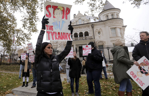 Stephanie Grant holds a "Stop the Tyranny" sign during a protest of Gov. Gary Herbert's mask mandate and new COVID-19 restrictions outside of the Governor's Mansion in Salt Lake City on Monday, Nov. 9, 2020.