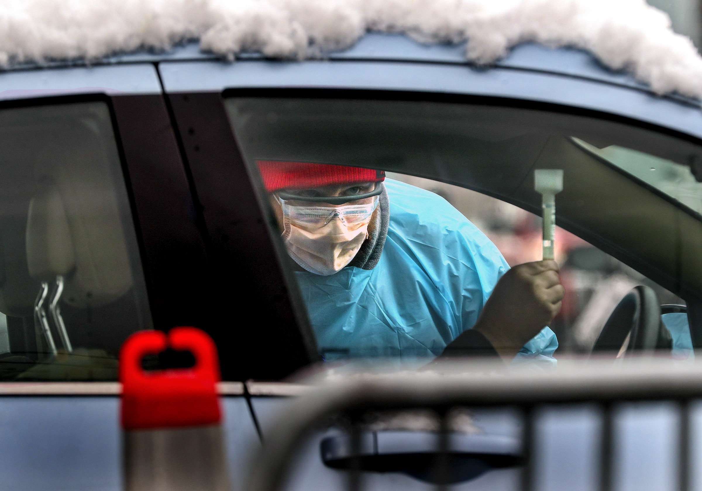 Spencer Moore, a medical assistant with University of Utah Health, checks a saliva sample as he administers a COVID-19 test at the Rice-Eccles Stadium testing site in Salt Lake City on Monday, Nov. 9, 2020.