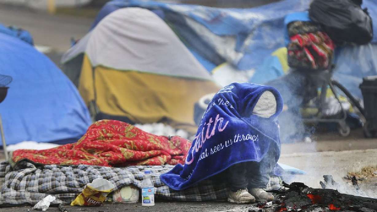 A homeless man bundles up near a fire on 700 South in Salt Lake City on Tuesday, Nov. 10, 2020. The Kem C. Gardner Policy Institute on Tuesday published a report identifying major problems within the state’s current homeless governance structure.