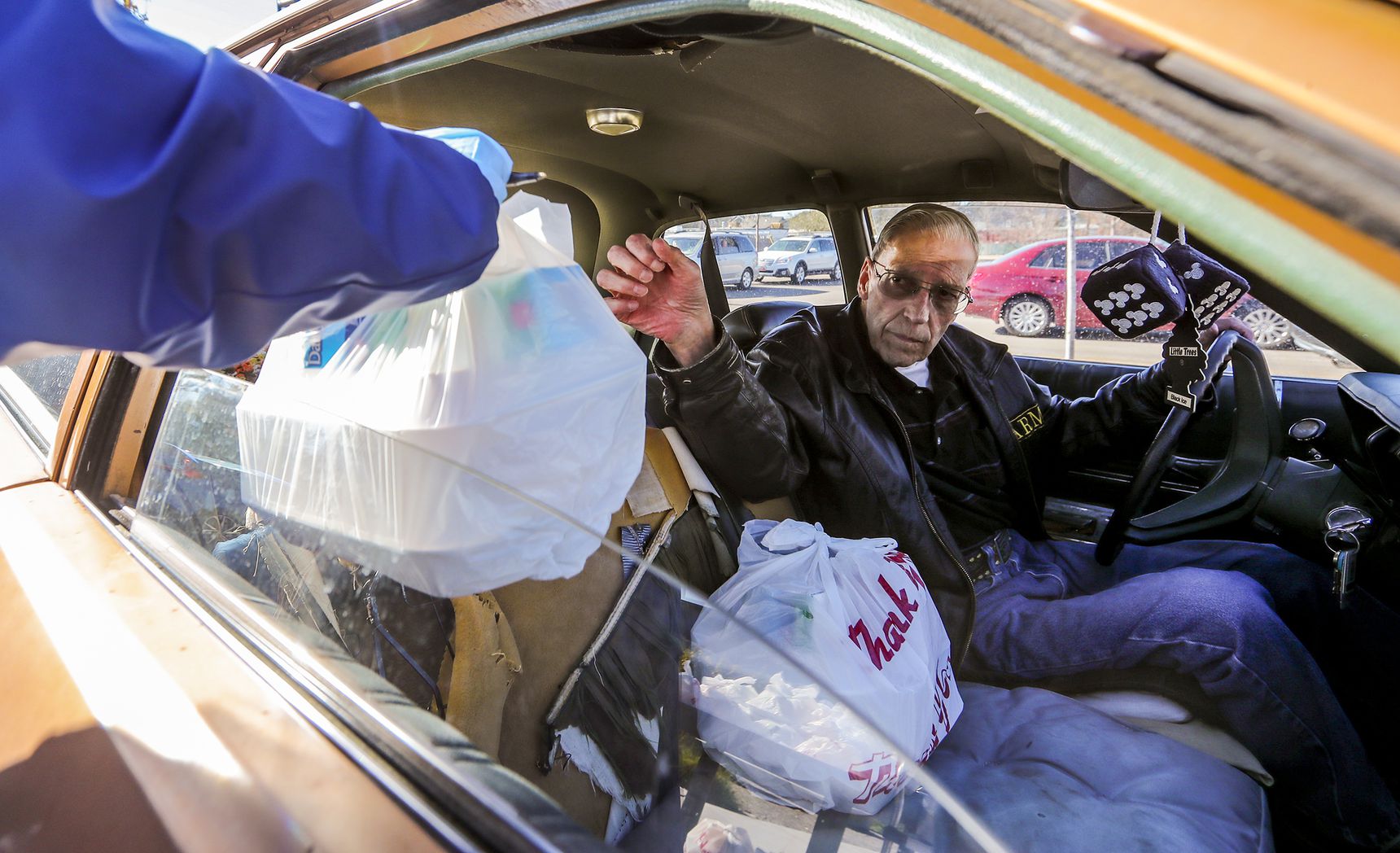 Dale Downs reaches out to take a bag of food from Kim Rasmussen, the center’s program coordinator, as seniors drive up and receive lunches at the Midvale Senior Center on Monday, Nov. 2, 2020.