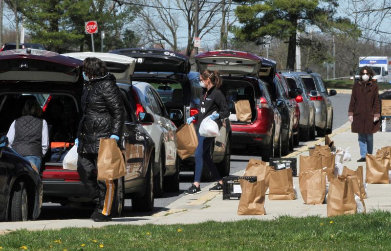 FILE PHOTO: Volunteers from the Student Support Network, an organization supplying food and clothing to families with school aged children in need, hand bags of donated food and supplies to families who don't have access to Baltimore County public schools food programs because the schools have been closed due to coronavirus restrictions in Parkville, Maryland, U.S. April 3, 2020.   REUTERS/Mitch Koppelman/File Photo