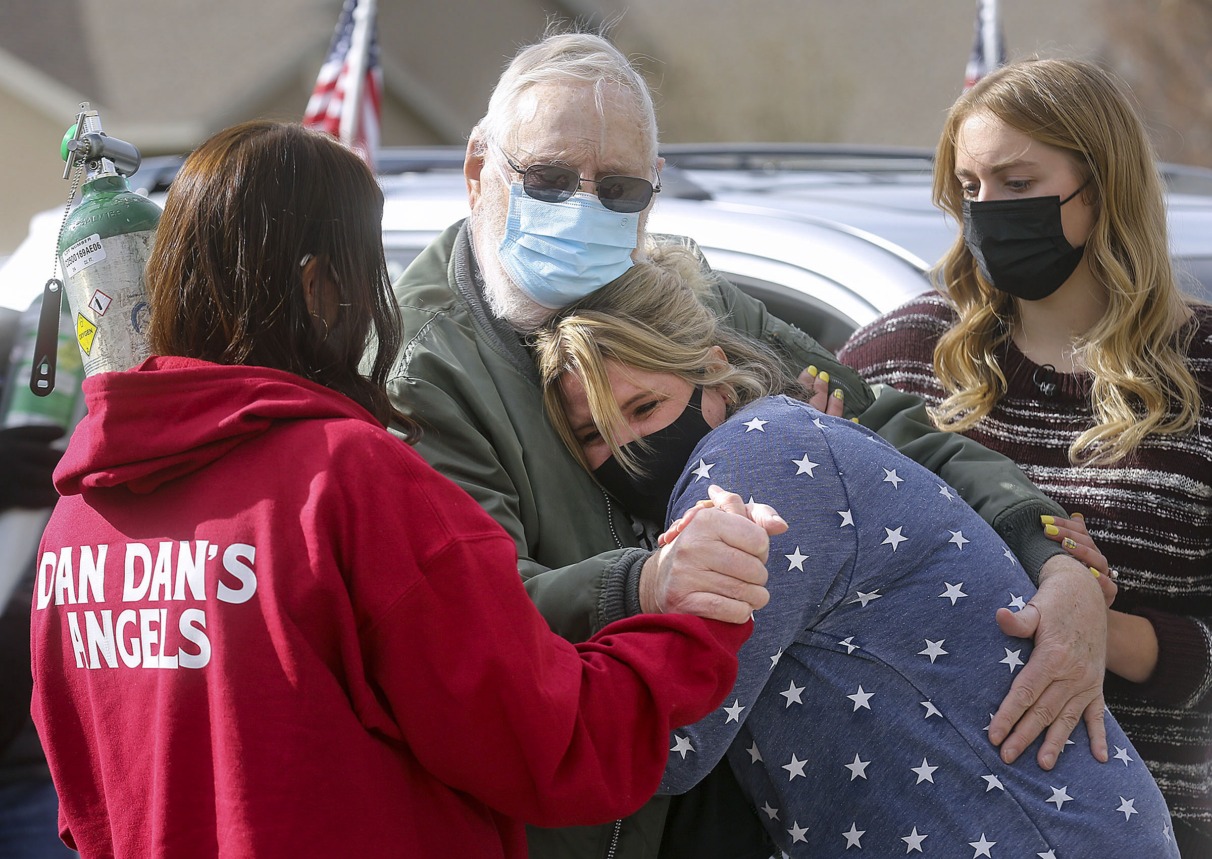 Vietnam veteran Warren Craig Eby hugs his friend and neighbor Kelcy Furey as daughter Alissa Allen left, holds his hand, and granddaughter Storme Cooper, right, holds his arm during a welcome home celebration in Saratoga Springs on Friday, Nov. 13, 2020. Eby was hospitalized for seven weeks with COVID-19.