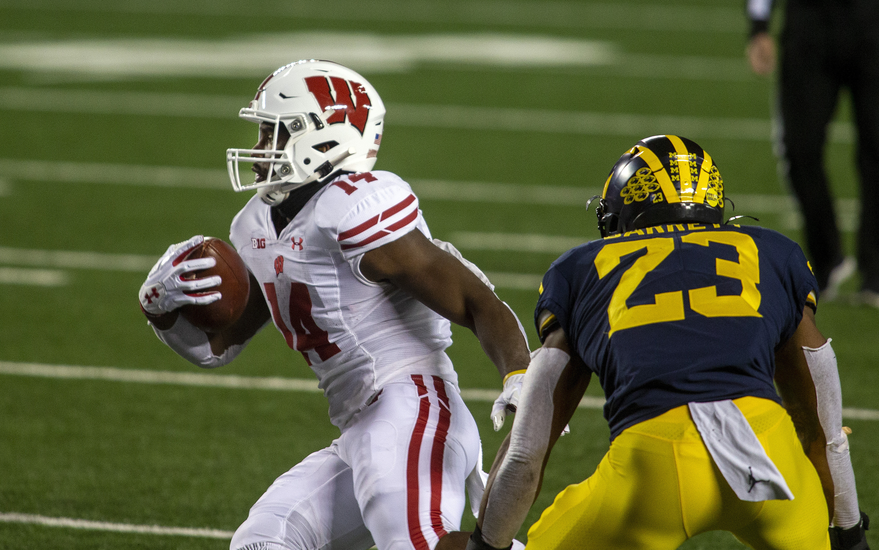Wisconsin running back Nakia Watson (14) rushes past Michigan linebacker Michael Barrett (23) in the first quarter of an NCAA college football game in Ann Arbor, Mich., Saturday, Nov. 14, 2020. (AP Photo/Tony Ding) [Nov-14-2020]