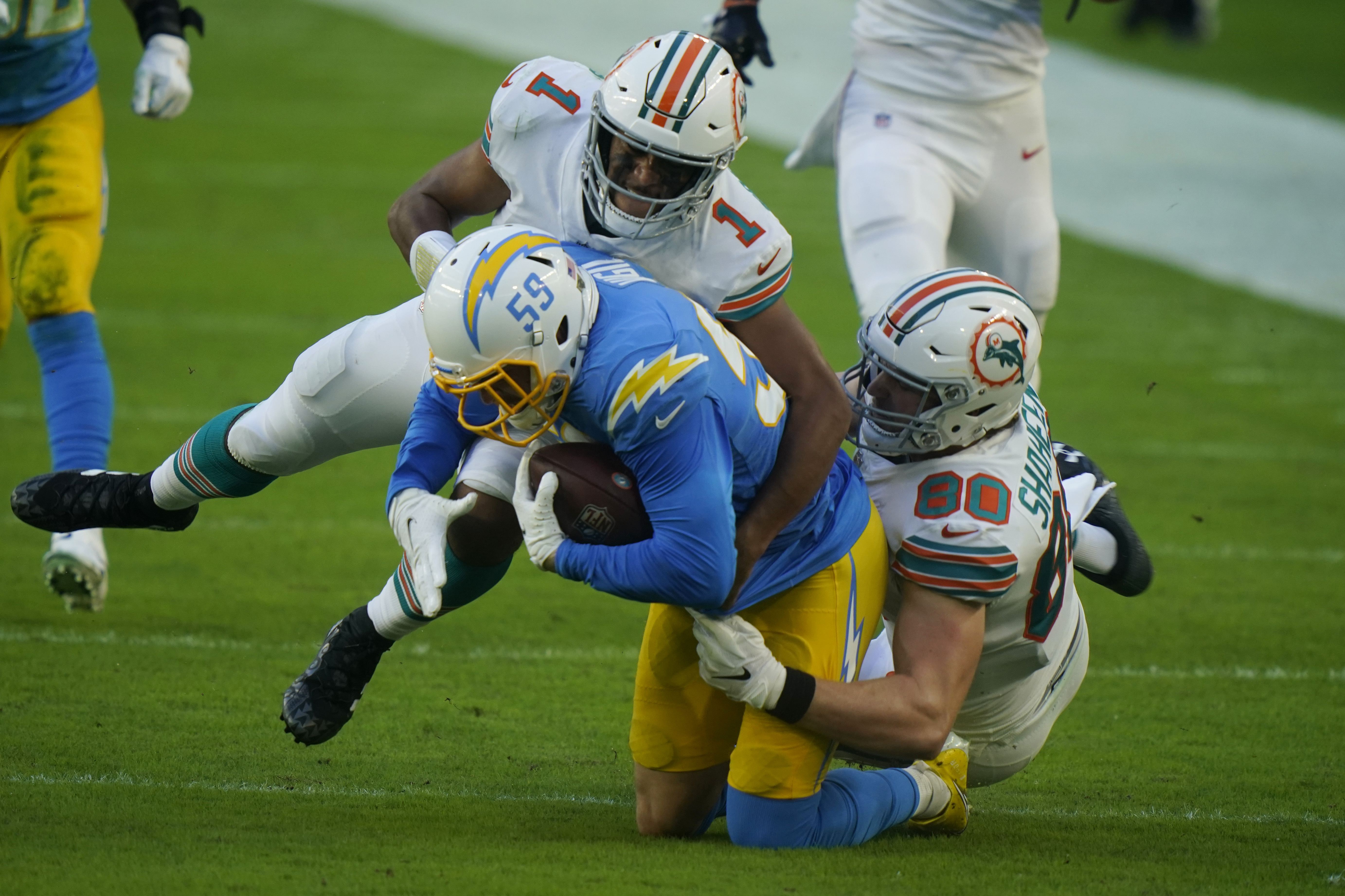 Miami Dolphins quarterback Tua Tagovailoa (1) and tight end Adam Shaheen (80) tackle Los Angeles Chargers outside linebacker Nick Vigil (59) after the Dolphins fumbled the ball, during the first half of an NFL football game, Sunday, Nov. 15, 2020, in Miami Gardens, Fla.
