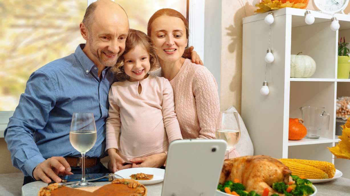 A happy family have a thanksgiving dinner and sends a video greeting to their parents by internet.