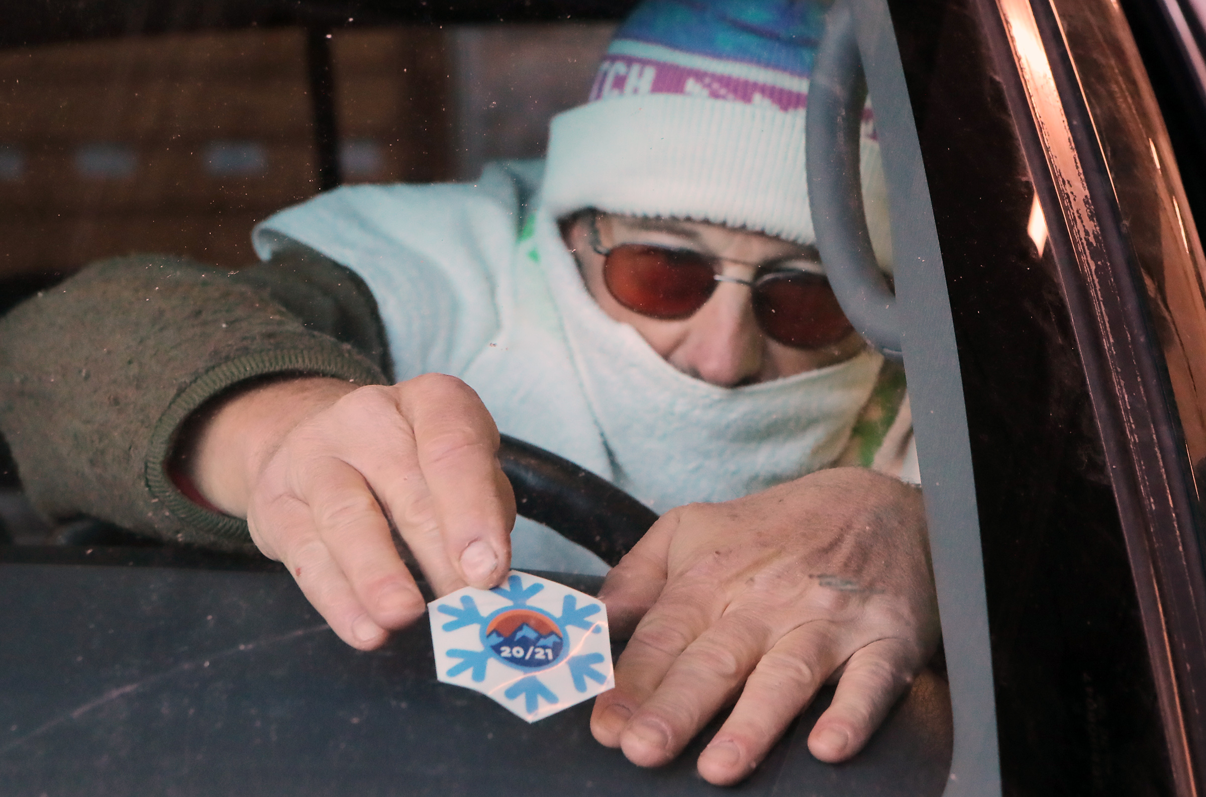 Daniel Sabo attaches a sticker on the inside of his windshield indicating his vehicle is properly equipped for winter weather at the Utah Department of Transportation maintenance shed in Cottonwood Heights on Monday, Nov. 16, 2020, as UDOT and the Unified Police Department relaunch the Cottonwood canyons sticker program.