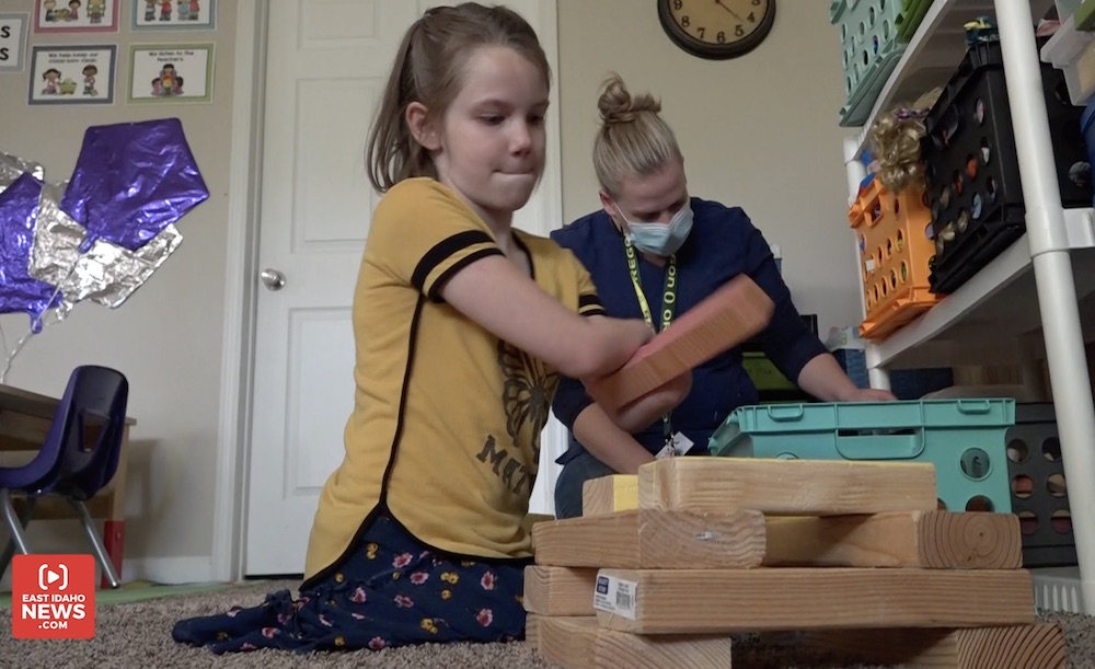 Rosalie Parker plays with blocks in her home while an aide helps assist with everyday tasks.