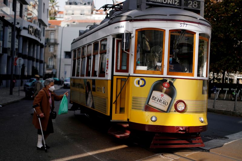 FILE PHOTO: A woman wearing a protective mask speaks with a driver of a tram during the coronavirus outbreak in Lisbon, Portugal, October 31, 2020.  REUTERS/Rafael Marchante