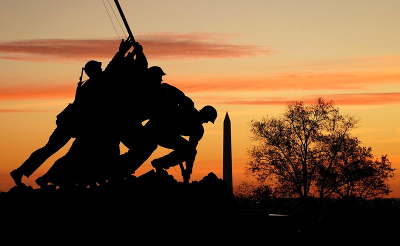 The sun rises behind the The United States Marine Corps War Memorial (Iwo Jima Memorial) and the Washington Monument in Washington, U.S., November 19, 2020.  REUTERS/Kevin Lamarque