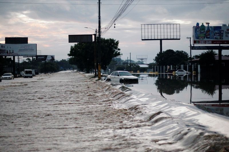 A stranded car is seen at a road flooded by the Chamelecon River due to heavy rain caused by Storm Iota, in La Lima, Honduras November 19, 2020. REUTERS/Jorge Cabrera