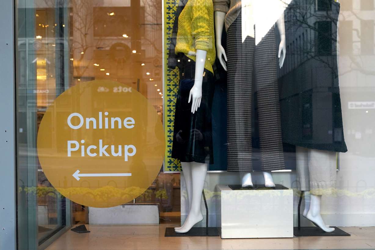 Mannequins stand on display Wednesday, Nov. 18, 2020, at the Ann Taylor store with an online pickup sign on Michigan Avenue in Chicago. The accelerating surge of coronavirus cases across the U.S. is causing an existential crisis for America’s retailers and spooking their customers just as the critically important holiday shopping season nears.